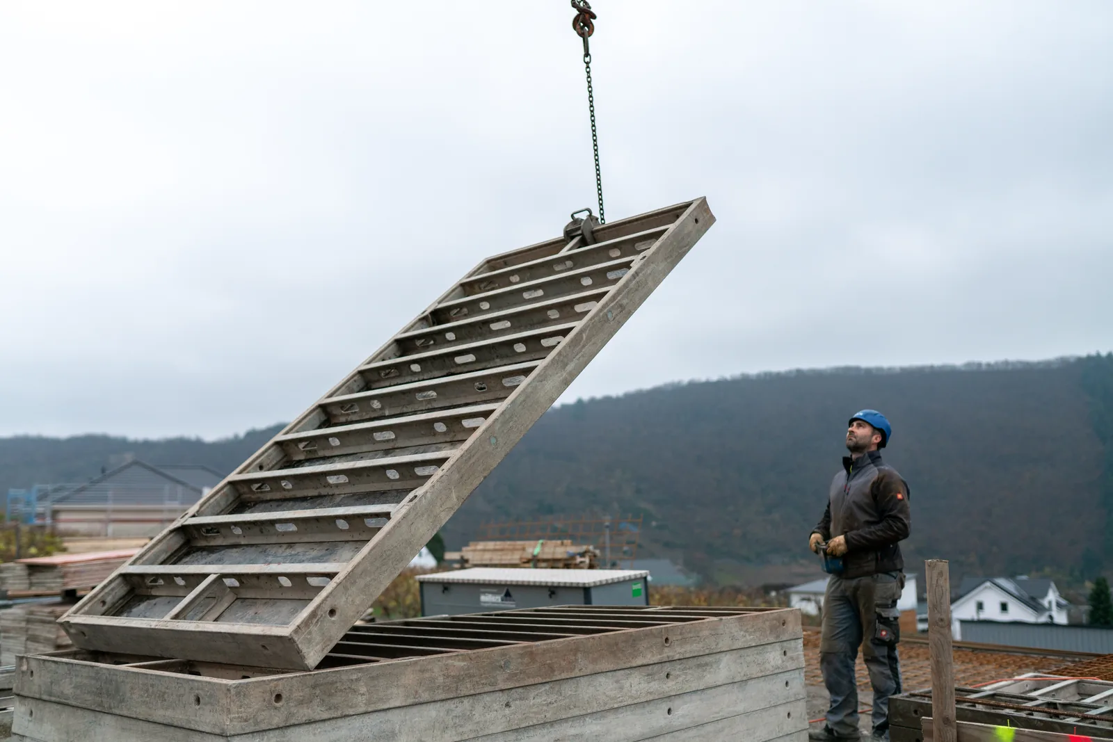 Müllers Bau – Team beim Versetzen eines Bauteils auf der Baustelle